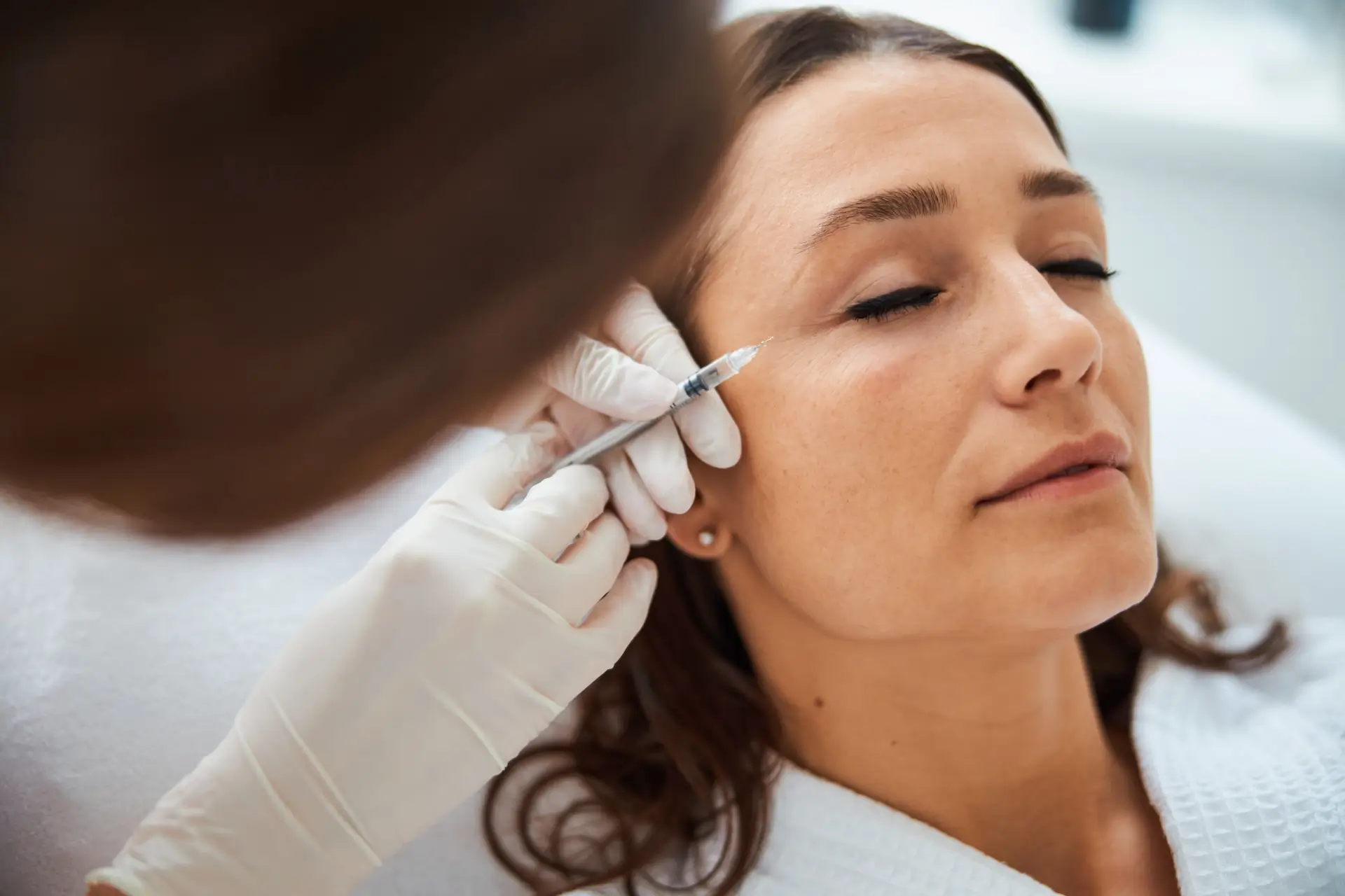 woman getting a botox injection around her eye
